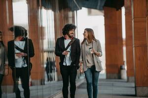 Business man and business woman talking and holding luggage traveling on a business trip, carrying fresh coffee in their hands.Business concept photo