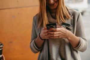 macro photo of a girl drinking coffee and using a cell phone during a break from work.