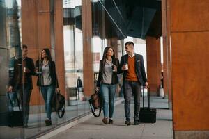 hombre de negocios y mujer de negocios hablando y sosteniendo equipaje viajando en un viaje de negocios, llevando café recién hecho en sus manos.concepto de negocio foto