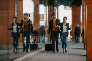 Business man and business woman talking and holding luggage traveling on a business trip, carrying fresh coffee in their hands.Business concept photo