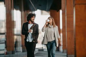 Business man and business woman talking and holding luggage traveling on a business trip, carrying fresh coffee in their hands.Business concept photo