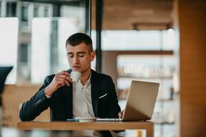 Happy business man sitting at cafeteria with laptop and smartphone photo