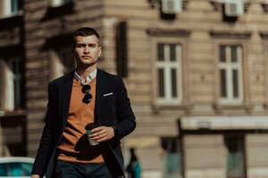 Going to airport terminal. Confident businessman traveler walking on city streets and pulling his suitcase drinking coffee and speaking on smartphone photo