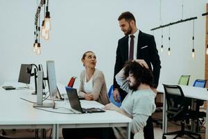Group of multi-ethnic colleagues working on desktop computers, laptop and sharing their ideas in a modern office space.Young influencers work on online marketing projects. photo