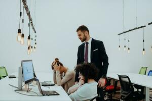 Group of multi-ethnic colleagues working on desktop computers, laptop and sharing their ideas in a modern office space.Young influencers work on online marketing projects. photo