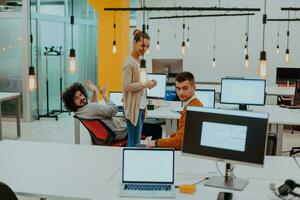 Group of multi-ethnic colleagues working on desktop computers, laptop and sharing their ideas in a modern office space.Young influencers work on online marketing projects. photo