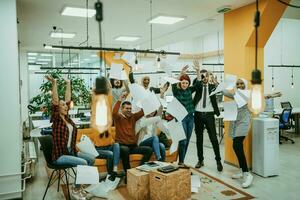 Group of business people throwing paper in air at modern startup office, team success and job done concept photo
