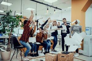 Group of business people throwing paper in air at modern startup office, team success and job done concept photo