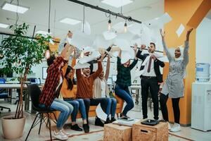 Group of business people throwing paper in air at modern startup office, team success and job done concept photo