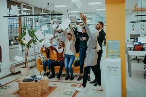 Group of business people throwing paper in air at modern startup office, team success and job done concept photo