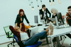 Group of multi-ethnic colleagues working on desktop computers, laptop and sharing their ideas in a modern office space.Young influencers work on online marketing projects. photo