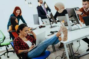 Group of multi-ethnic colleagues working on desktop computers, laptop and sharing their ideas in a modern office space.Young influencers work on online marketing projects. photo