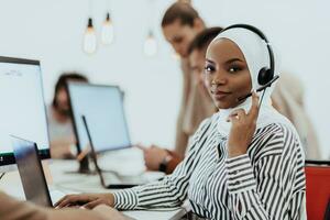 African American muslim woman with hijab and headset working as customer support in a modern office. photo