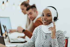 African American muslim woman with hijab and headset working as customer support in a modern office. photo