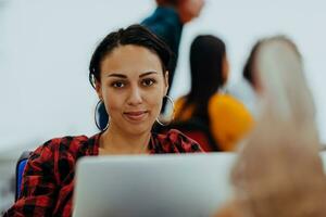 Happy woman working on laptop in modern office surrounded by friends photo