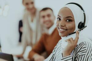 African American muslim woman with hijab and headset working as customer support in a modern office. photo