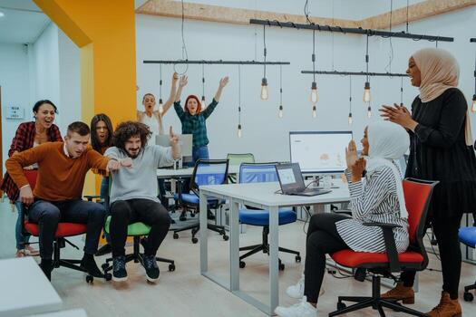 Team building and office fun. Young cheerful businesspeople in smart casual wear having fun while racing on office chairs and smiling. photo