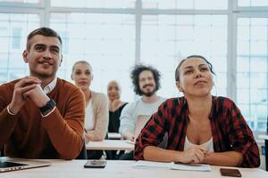 un grupo de diverso joven hombres y mujer sentar en un moderno salón de clases y escucha a un conferencia en negocio formación foto