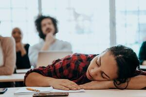 cansado mujer siesta en el mesa durante un conferencia en el salón de clases foto