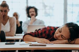 cansado mujer siesta en el mesa durante un conferencia en el salón de clases foto
