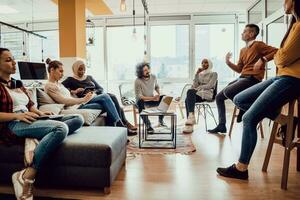 Young designer giving some new ideas about project to his partners in conference room. Business people discussing over new business project in office. photo