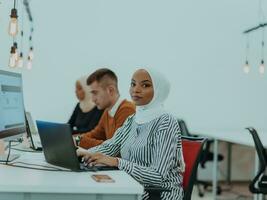 Group of multi-ethnic colleagues working on desktop computers, laptop and sharing their ideas in a modern office space.Young influencers work on online marketing projects. photo