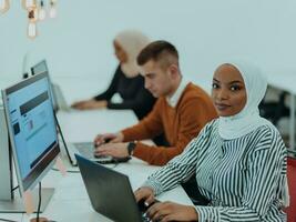 Group of multi-ethnic colleagues working on desktop computers, laptop and sharing their ideas in a modern office space.Young influencers work on online marketing projects. photo