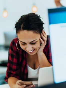 Woman sitting at workplace desk holds smartphone staring at laptop, synchronize data between computer and gadget in office, using corporate devices and business application, plan work, using organizer photo
