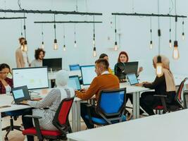 Group of multi-ethnic colleagues working on desktop computers, laptop and sharing their ideas in a modern office space.Young influencers work on online marketing projects. photo