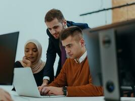 Group of multi-ethnic colleagues working on desktop computers, laptop and sharing their ideas in a modern office space.Young influencers work on online marketing projects. photo