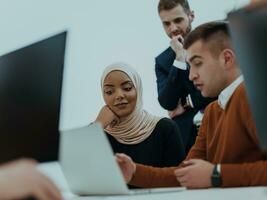 Group of multi-ethnic colleagues working on desktop computers, laptop and sharing their ideas in a modern office space.Young influencers work on online marketing projects. photo