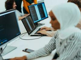 Group of multi-ethnic colleagues working on desktop computers, laptop and sharing their ideas in a modern office space.Young influencers work on online marketing projects. photo