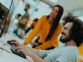 Group of multi-ethnic colleagues working on desktop computers, laptop and sharing their ideas in a modern office space.Young influencers work on online marketing projects. photo