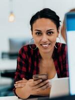 Woman sitting at workplace desk holds smartphone staring at laptop, synchronize data between computer and gadget in office, using corporate devices and business application, plan work, using organizer photo