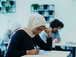 Photo of an African American Muslim woman being educated about business development in a modern classroom