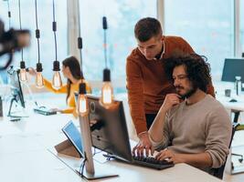 Two men discuss a project while looking at a computer monitor in a modern office photo