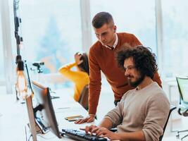 Two men discuss a project while looking at a computer monitor in a modern office photo