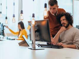 Two men discuss a project while looking at a computer monitor in a modern office photo