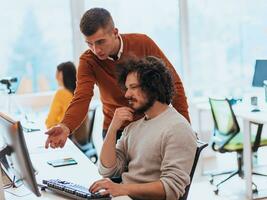 Two men discuss a project while looking at a computer monitor in a modern office photo