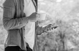 Clouseup of young man using mobile and drinking coffe photo
