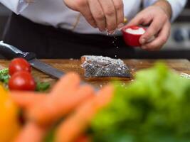 Chef hands preparing marinated Salmon fish photo