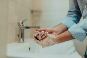 hombre utilizando jabón y Lavado manos debajo el agua grifo. higiene concepto mano de cerca detalle. foto