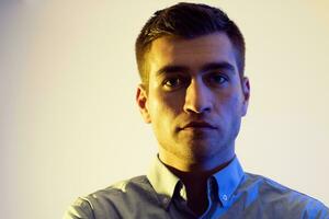 A man in a shirt poses on a dark multicolored neon background photo