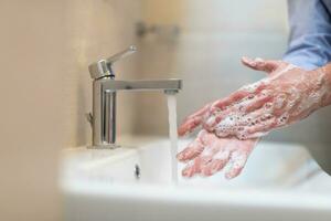 Man using soap and washing hands under the water tap. Hygiene concept hand closeup detail. photo