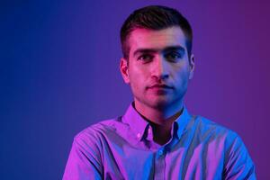 A man in a shirt poses on a dark multicolored neon background photo