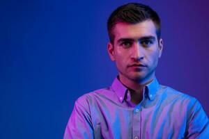 A man in a shirt poses on a dark multicolored neon background photo