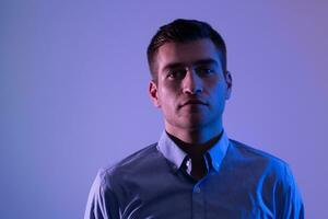 A man in a shirt poses on a dark multicolored neon background photo