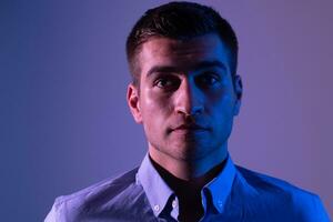 A man in a shirt poses on a dark multicolored neon background photo