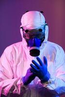 Coronavirus covid-19 pandemic. Doctor scientist wearing protective biological suit and mask due to global healthcare epidemic warning and danger background in blue and pink neon lights background. photo