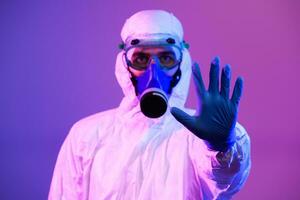 coronavirus covid-19 pandemia. médico científico vistiendo protector biológico traje y máscara debido a global cuidado de la salud epidemia advertencia y peligro antecedentes en azul y rosado neón luces antecedentes. foto